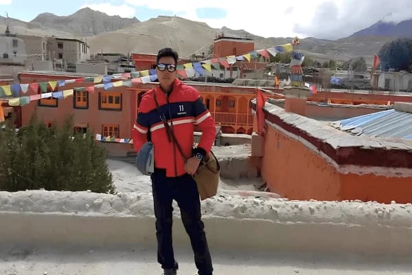 Trekker-standing-in-front-of-traditional-red-buildings-and-prayer-flags-in-Lo-Manthang-Upper-Mustang