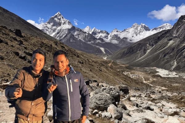 Two-trekkers-posing-on-a-Himalayan-valley-trail-with-snow-capped-mountain-peaks-in-the-background