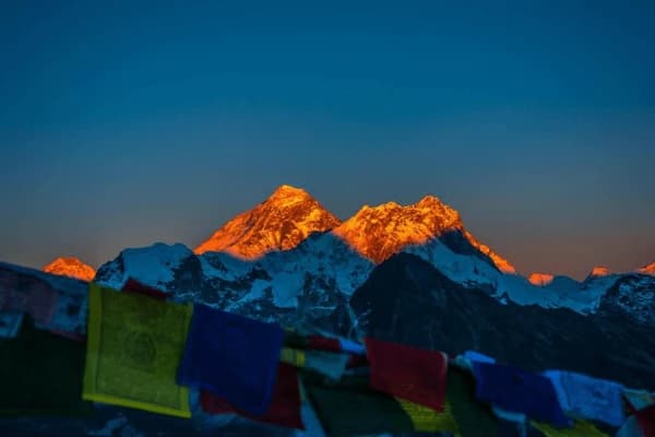 Sunrise over Everest Mountain surround peaks in the Himalayas with colorful prayer flag in the foreground