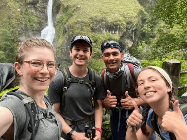 Group-of-trekkers-posing-in-front-of-a-waterfall-during-a-Nepal-trekking-adventure